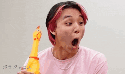 a man in a pink shirt is holding a yellow toy chicken