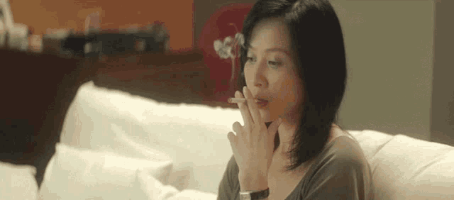 a woman smoking a cigarette while sitting on a couch