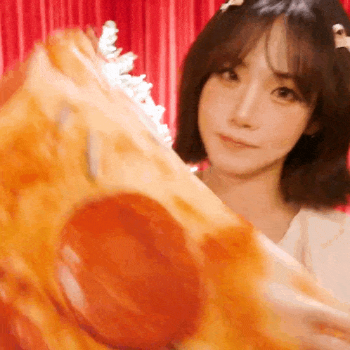 a woman is holding a slice of pepperoni pizza in front of her face