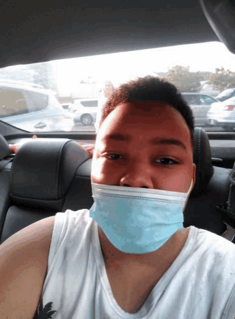 a man wearing a blue face mask is sitting in the back seat of a car
