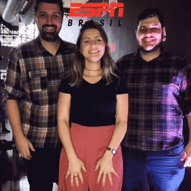 three people posing for a picture in front of a sign that says brasil