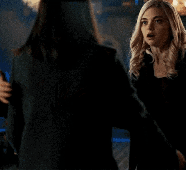 two women are hugging each other in a dark room in a dark room .