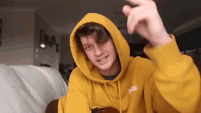 a man in a yellow hoodie is sitting on a couch