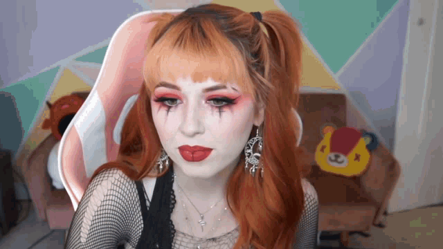 a woman with red hair is wearing a black shirt and earrings