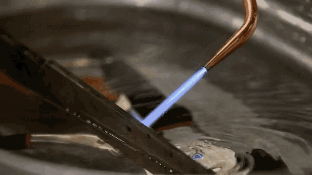 a blue flame is coming out of a copper pipe in a sink