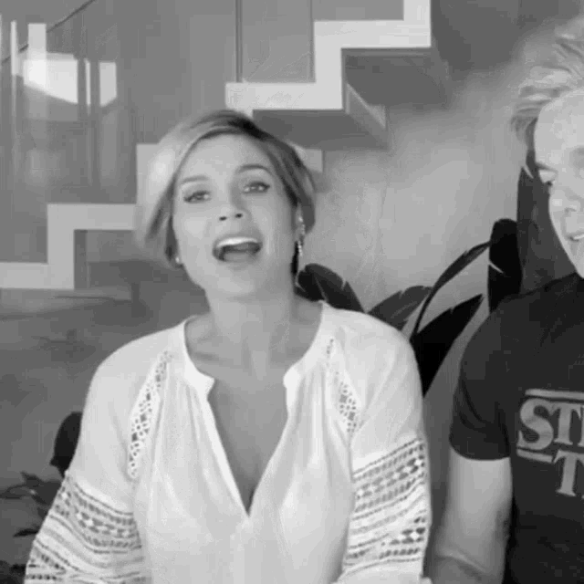 a black and white photo of a woman wearing a white shirt and a man wearing a black shirt with the word st on it