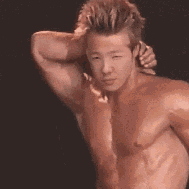 a shirtless man with his hand on his head looks at the camera