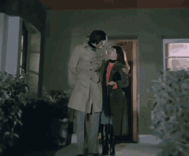 a man and a woman are standing in front of a doorway