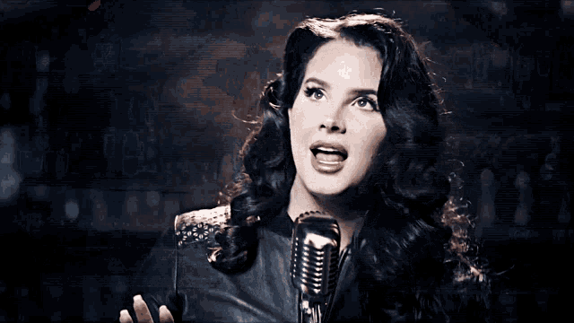 a woman singing into a microphone while wearing a black leather jacket