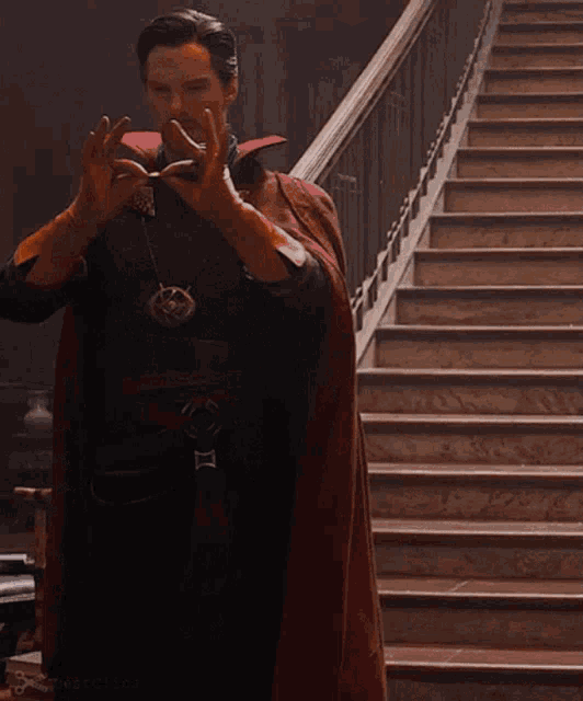 a man in a red cape is standing on a set of stairs