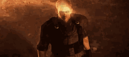 a man in a mask is standing in front of a fire in a dark room .