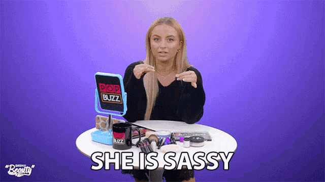 a woman sitting at a table with a mirror and a box that says pop buzz on it