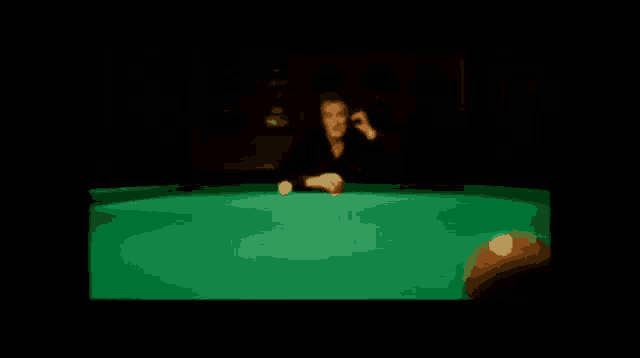 a man is playing pool in a dark room