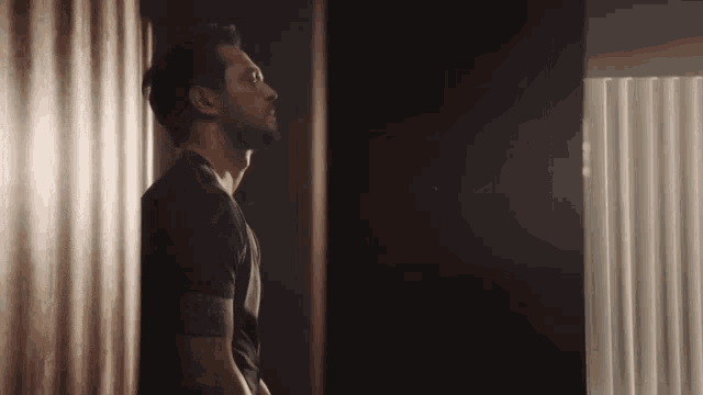 a man leaning against a wall looking out of a window
