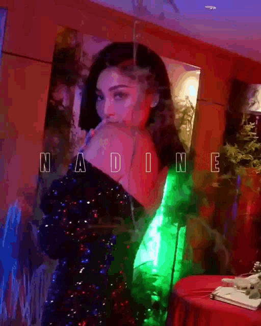 a woman in a green sequined dress is standing in front of a mirror with the name nadine written on it