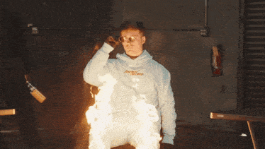 a man wearing a white hoodie with the word supreme on it is surrounded by flames