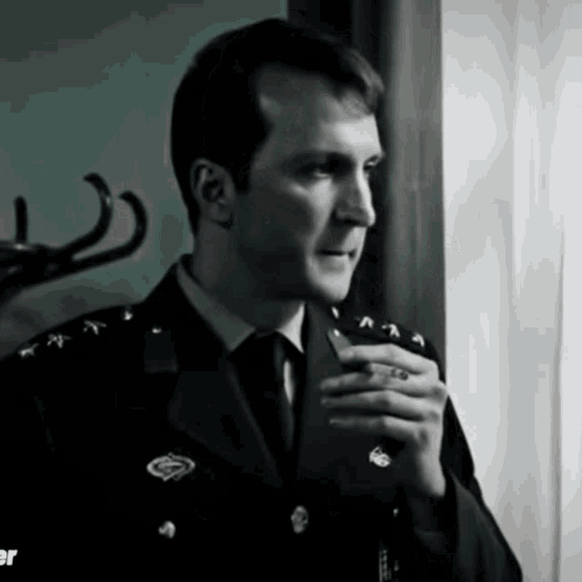 a man in a military uniform is holding a cell phone in his hand