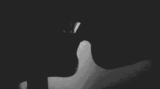 a black and white photo of a man and a woman kissing in the dark .