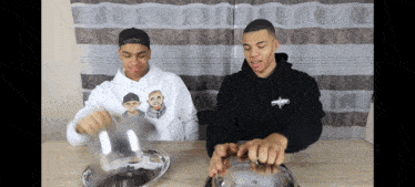 a man wearing a hoodie that says ' snoop dogg ' on it sits next to another man