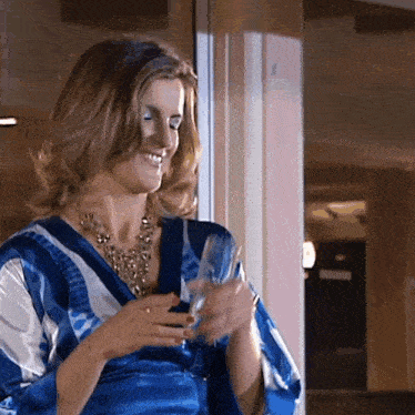 a woman in a blue and white striped shirt is holding a glass