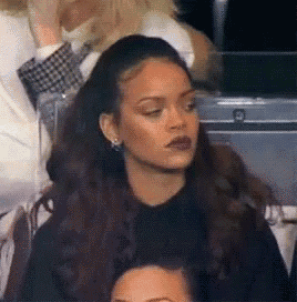 a woman is sitting in a crowd of people and making a face .