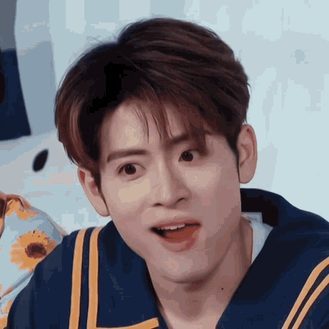 a young man with a surprised look on his face is wearing a blue and yellow jacket .
