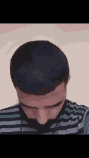 a man with a striped shirt and a beard is looking down