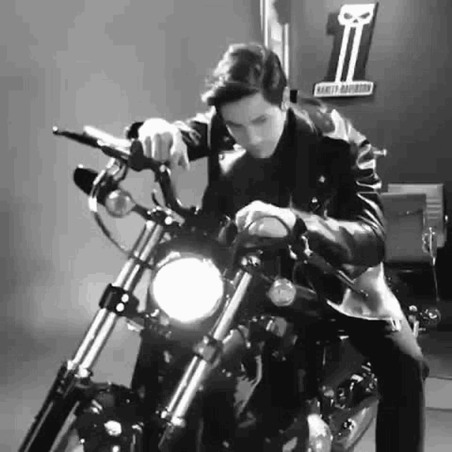 a man is sitting on a harley davidson motorcycle in a black and white photo .