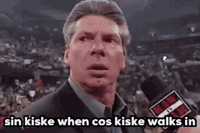 a man in a suit is talking into a microphone with the words sin kiske when cos kiske walks in .