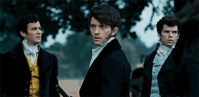 three men in suits are standing next to each other and one of them is holding a gun