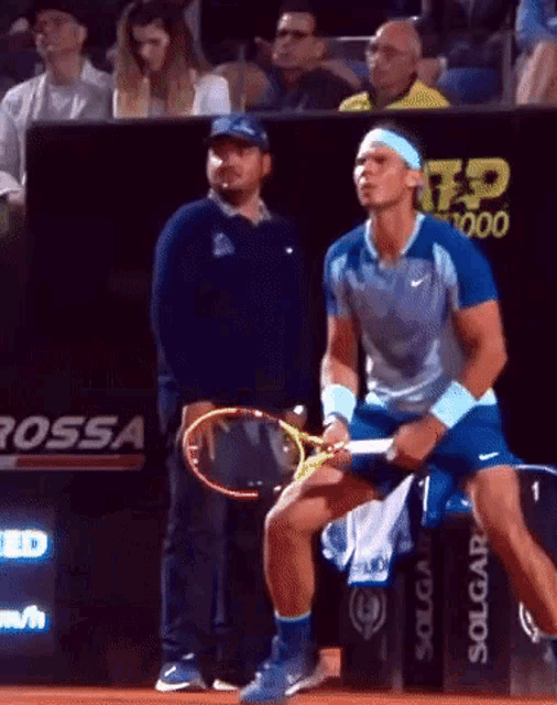 a man holding a tennis racquet in front of a sign that says solgar
