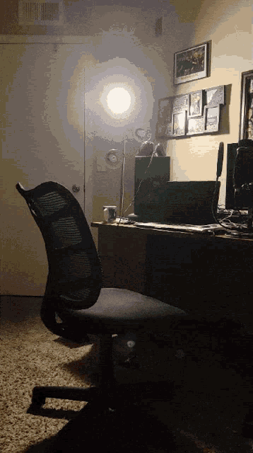 a chair sits in front of a desk with a laptop and a lamp