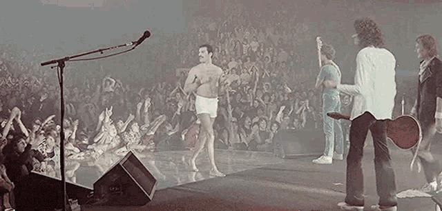 a man without a shirt is dancing on stage in front of a crowd .