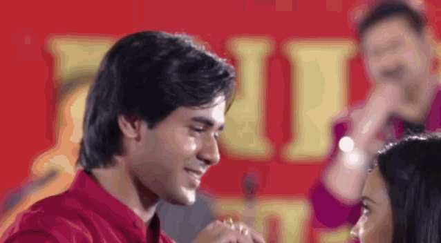 a man in a red shirt is holding a woman 's hand in front of a band .