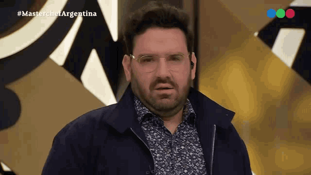 a man wearing glasses and a jacket is appearing on a television show called masterchef argentina