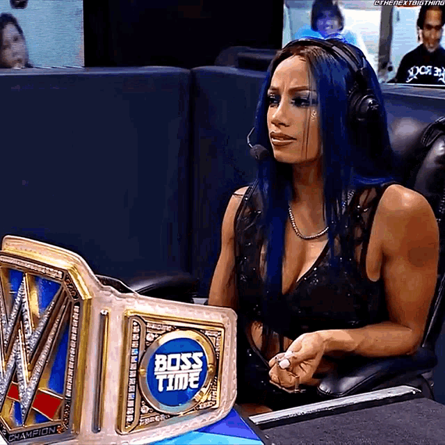 a woman with blue hair is sitting in a chair with a boss time belt in front of her