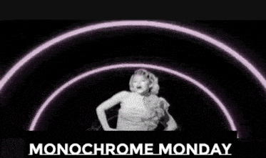 a woman in a white dress is standing in a tunnel with the words monochrome monday below her .