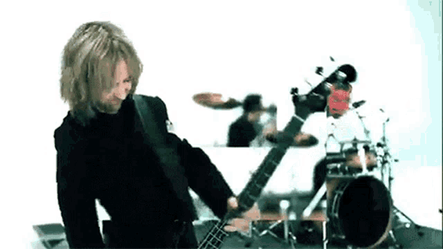 a man is playing a guitar in front of a drum set and a drummer .