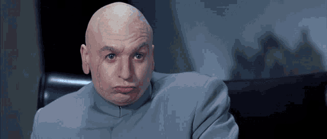 a bald man in a gray suit is making a face