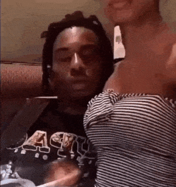 a man and a woman are sitting on a couch . the woman is wearing a striped shirt .