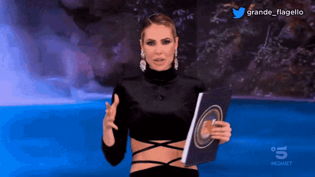 a woman in a black top is holding a book in front of a waterfall and the words grande flagello