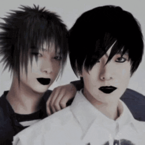 a couple of people with black hair and black lipstick are standing next to each other .