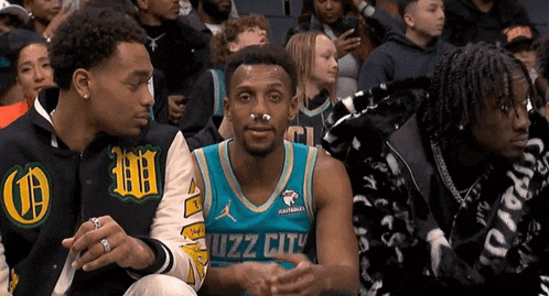 a man wearing a jersey that says buzz city sits in the stands