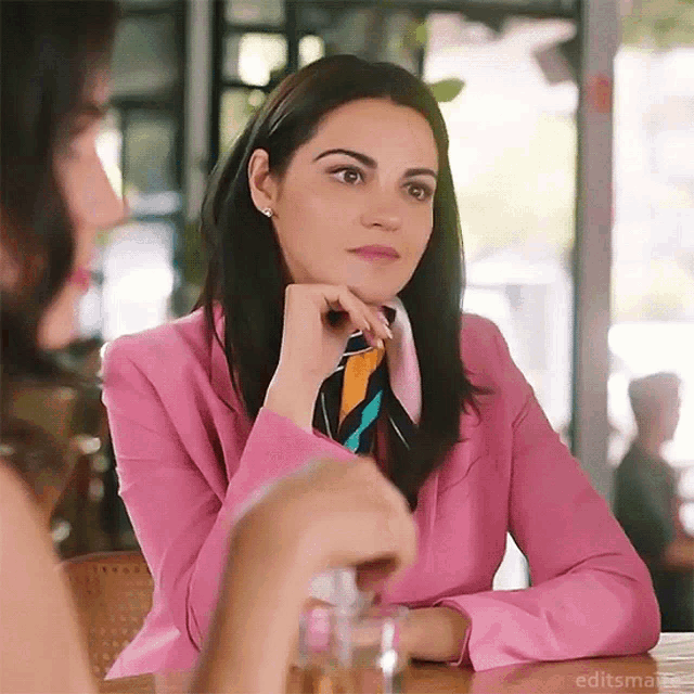 a woman in a pink jacket is sitting at a table with another woman .