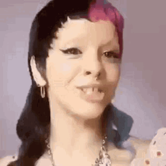 a close up of a woman 's face with a piercing in her nose and a necklace .