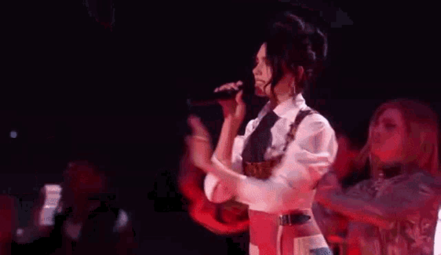 a group of people are dancing on a stage with red spotlights behind them