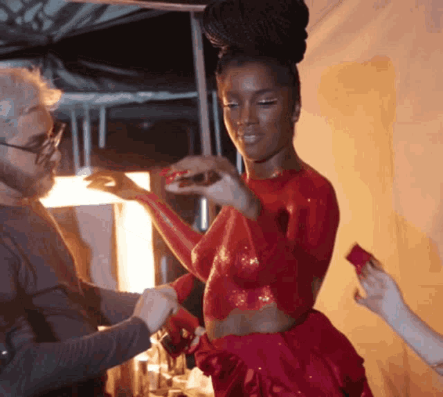 a woman in a red dress is getting her body painted