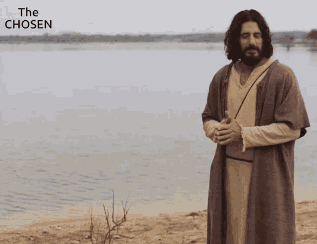 a man in a robe stands in front of a body of water with the words the chosen above him