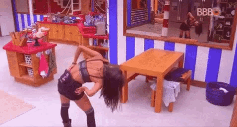 a woman is dancing in a room with a table and a striped wall .