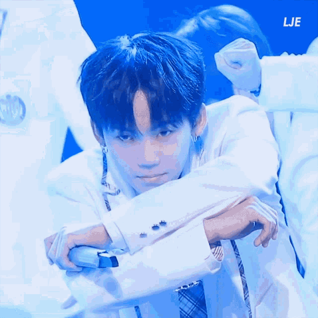 a boy with blue hair is holding a microphone with lje written on the bottom right